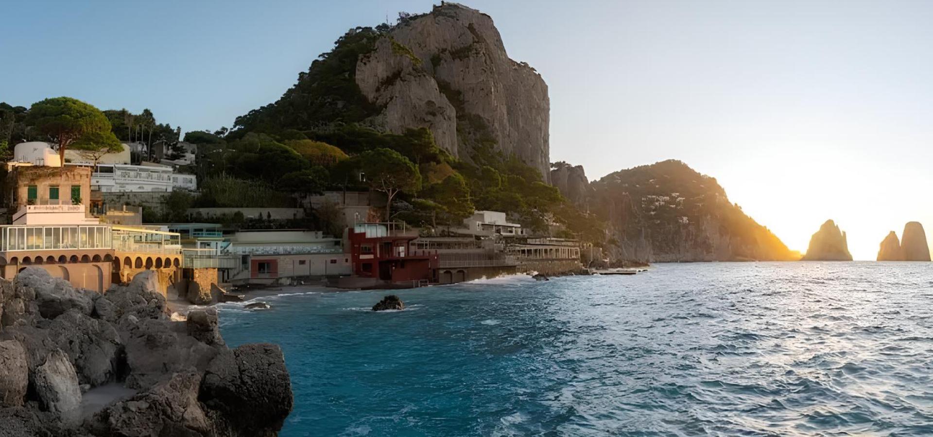 Tramonto su Capri: mare blu, scogli imponenti e ville immerse nel verde lussureggiante.