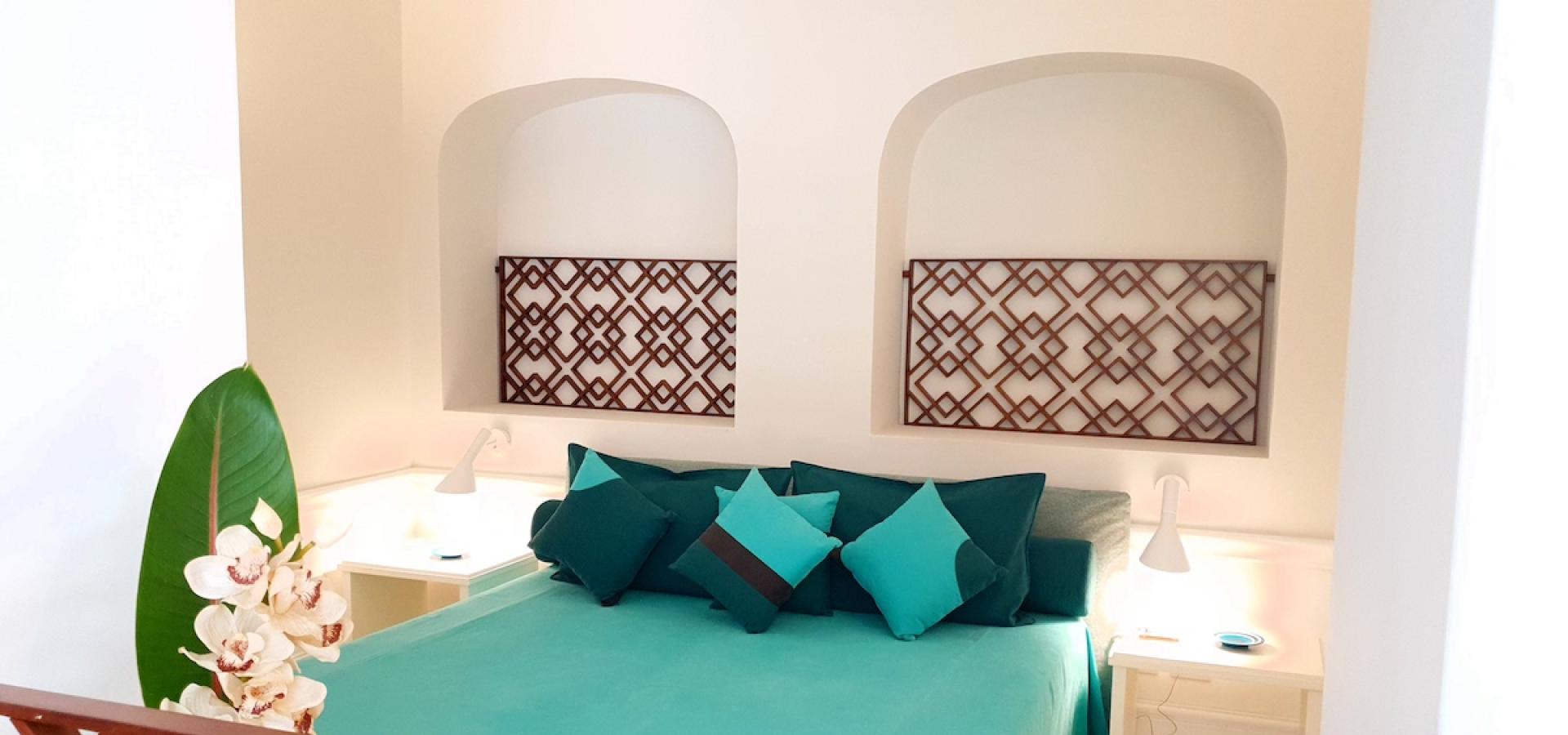 Camera luminosa con letto verde acqua e decorazioni eleganti, atmosfera rilassante.