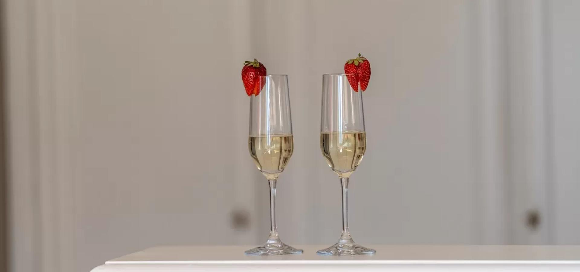 Due calici di champagne con fragole, eleganza e romanticismo in un'atmosfera intima.