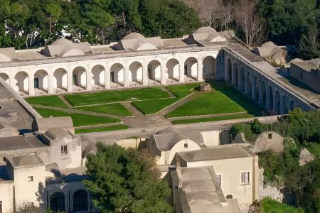 Antico chiostro con archi bianchi, immerso nel verde, emana serenità e storia.