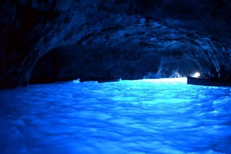 Una grotta marina illuminata da un'acqua blu brillante, creando un'atmosfera magica e surreale.