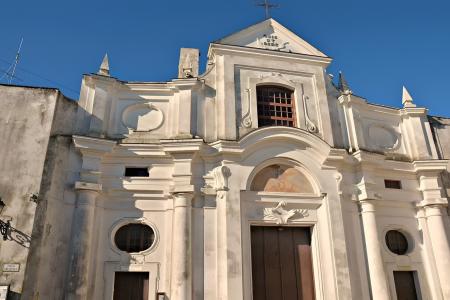 Facciata barocca di una chiesa, bianca e imponente, sotto un cielo azzurro intenso.