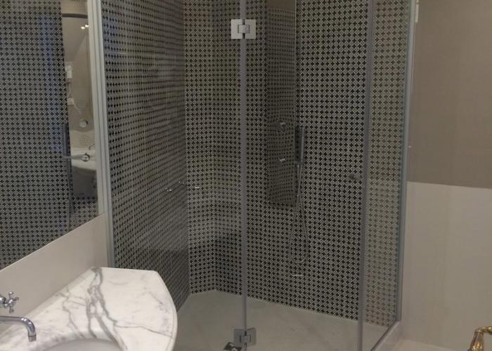 Elegante bagno moderno con doccia angolare e lavabo in marmo, atmosfera sofisticata.
