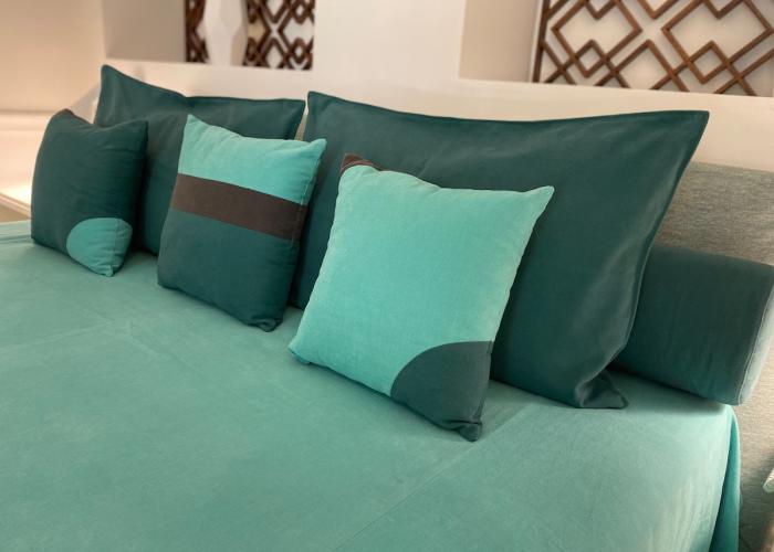Cuscini verde acqua su letto elegante, atmosfera rilassante e accogliente.