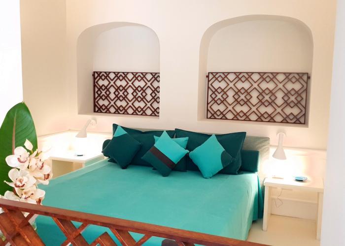 Letto elegante con cuscini turchesi, atmosfera rilassante e dettagli decorativi raffinati.