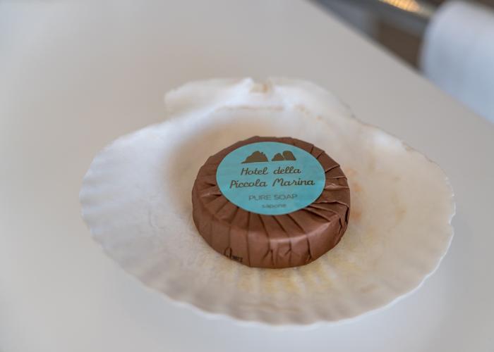 Sapone avvolto in carta marrone su conchiglia, evoca eleganza e semplicità marina.
