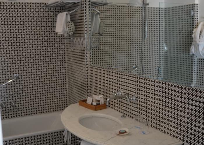 Bagno elegante con piastrelle geometriche bianche e nere, atmosfera sofisticata e accogliente.