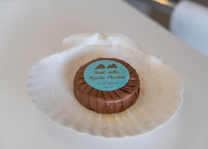 Sapone incartato su conchiglia, evoca eleganza e accoglienza marina.