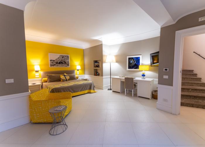 Camera luminosa e accogliente con dettagli gialli, perfetta per relax e creatività.