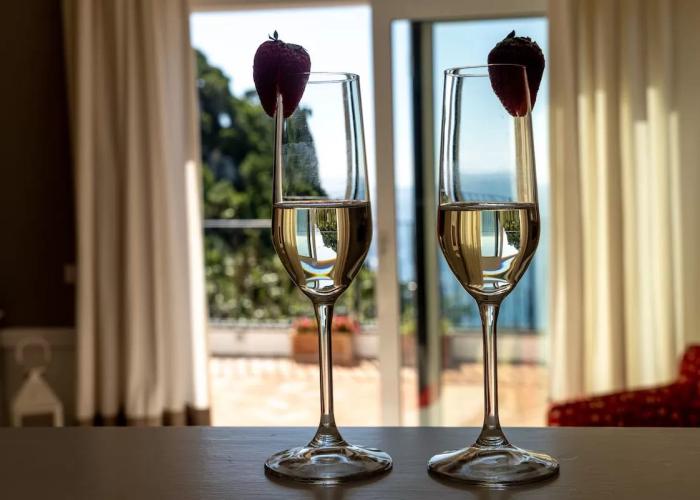 Due calici di champagne con fragole, vista mare da una finestra aperta.