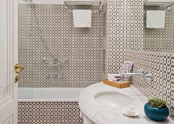 Bagno elegante con piastrelle geometriche, lavabo in marmo e dettagli moderni, atmosfera raffinata.